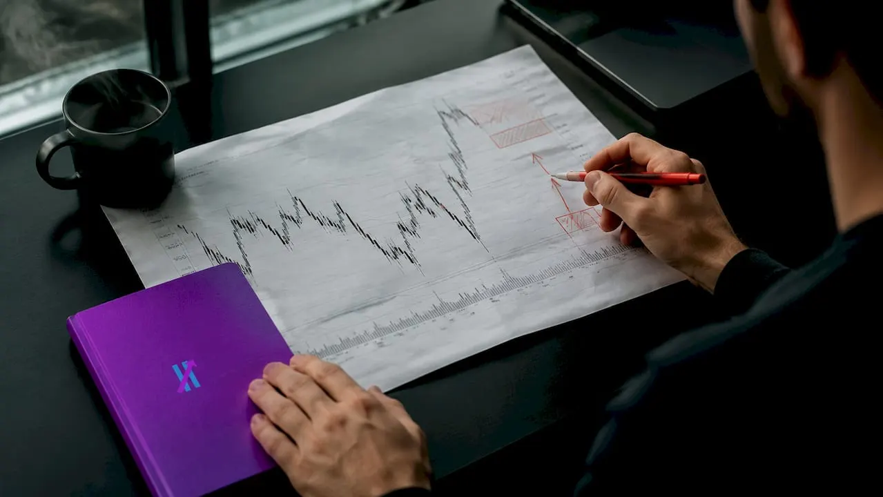Hands annotating trading chart close-up