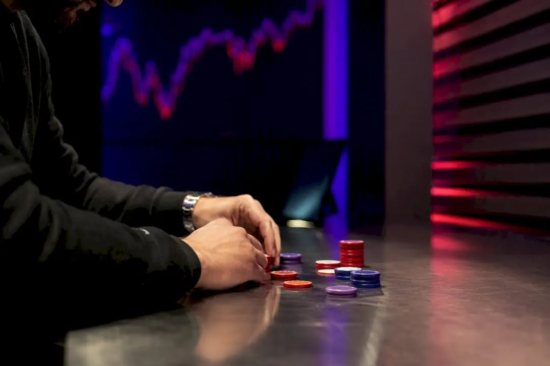 Hands sizing down trading chips on dark desk