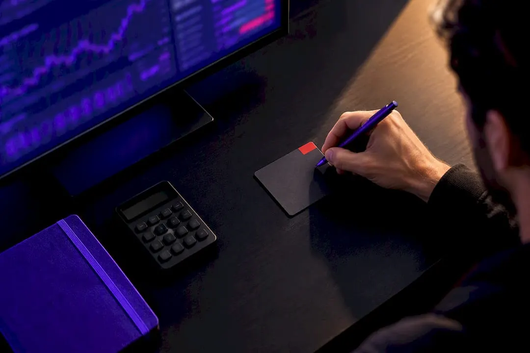 Trader writing risk rules beside monitor
